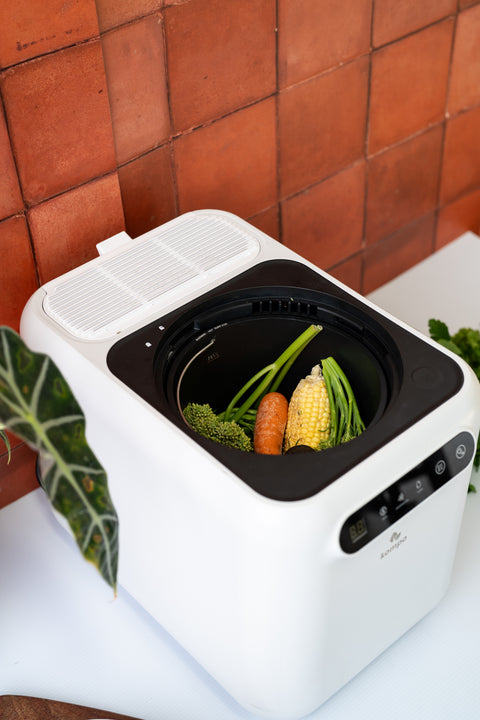 White food dehydrator with vegetables on a tiled wall background