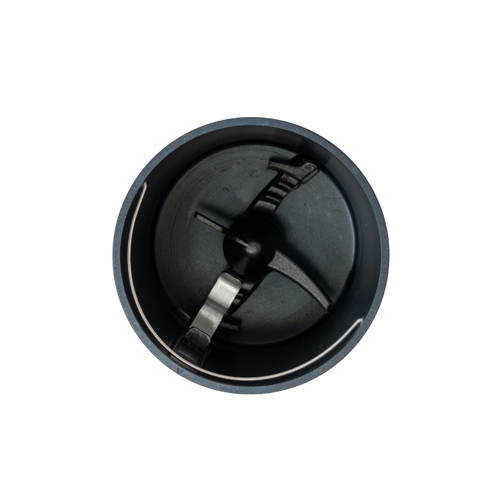 Top-down view of an empty circular dark grey grinder chamber with a metal blade and, isolated on a white background.